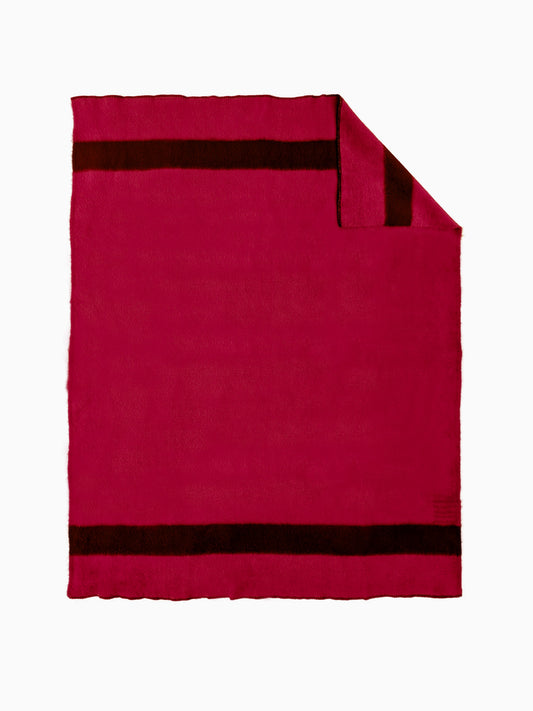 A handwoven striped wool throw blanket in solid magenta-red with black stripes, and a flipped corner.
