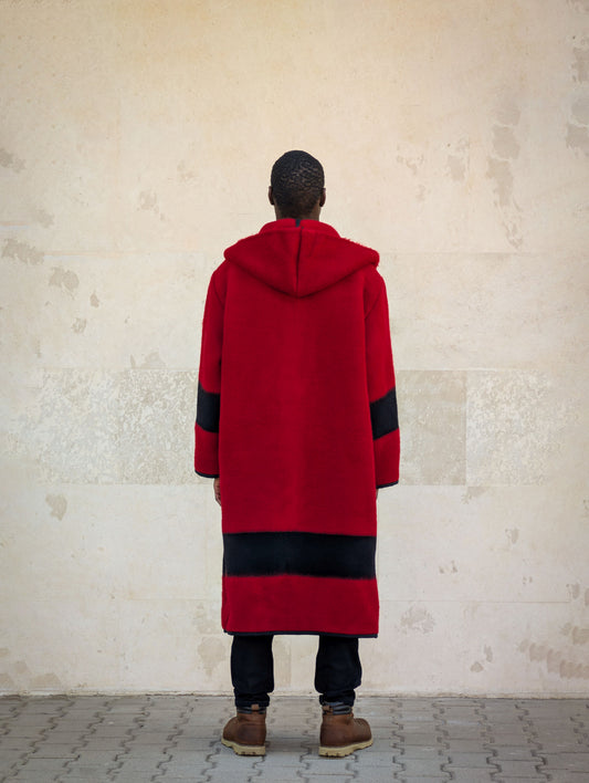 Back view of red hooded wool blanket coat with black stripe hem and long relaxed silhouette