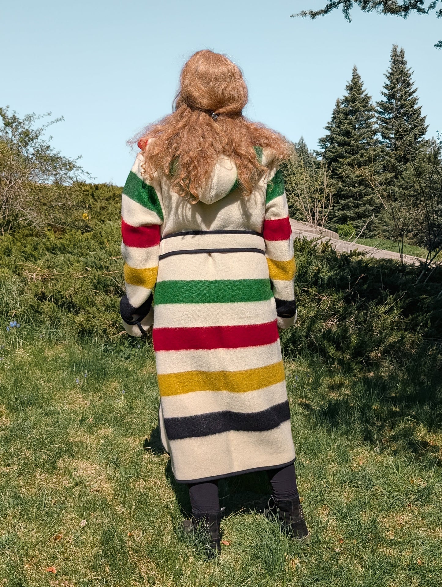Woman wearing a colorful unisex striped wrap robe coat standing backwards.
