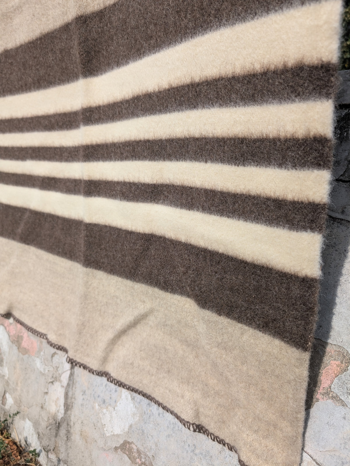 A closeup of an oatmeal wool blanket cabin throw, featuring many stripes in earth tones.