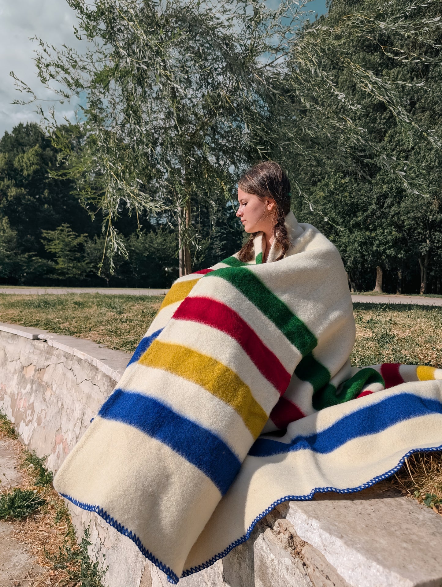 A girl at mid-length wrapped in a heritage cream wool blanket with colorful stripes, perfect for reenactment and rendezvous