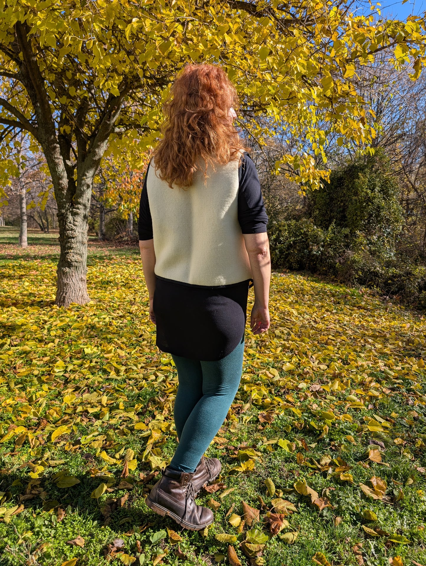 Woman standing with her back, wearing a made-to-order wool blanket vest, upcycled from a new ivory wool blanket with a black stripe in front.
