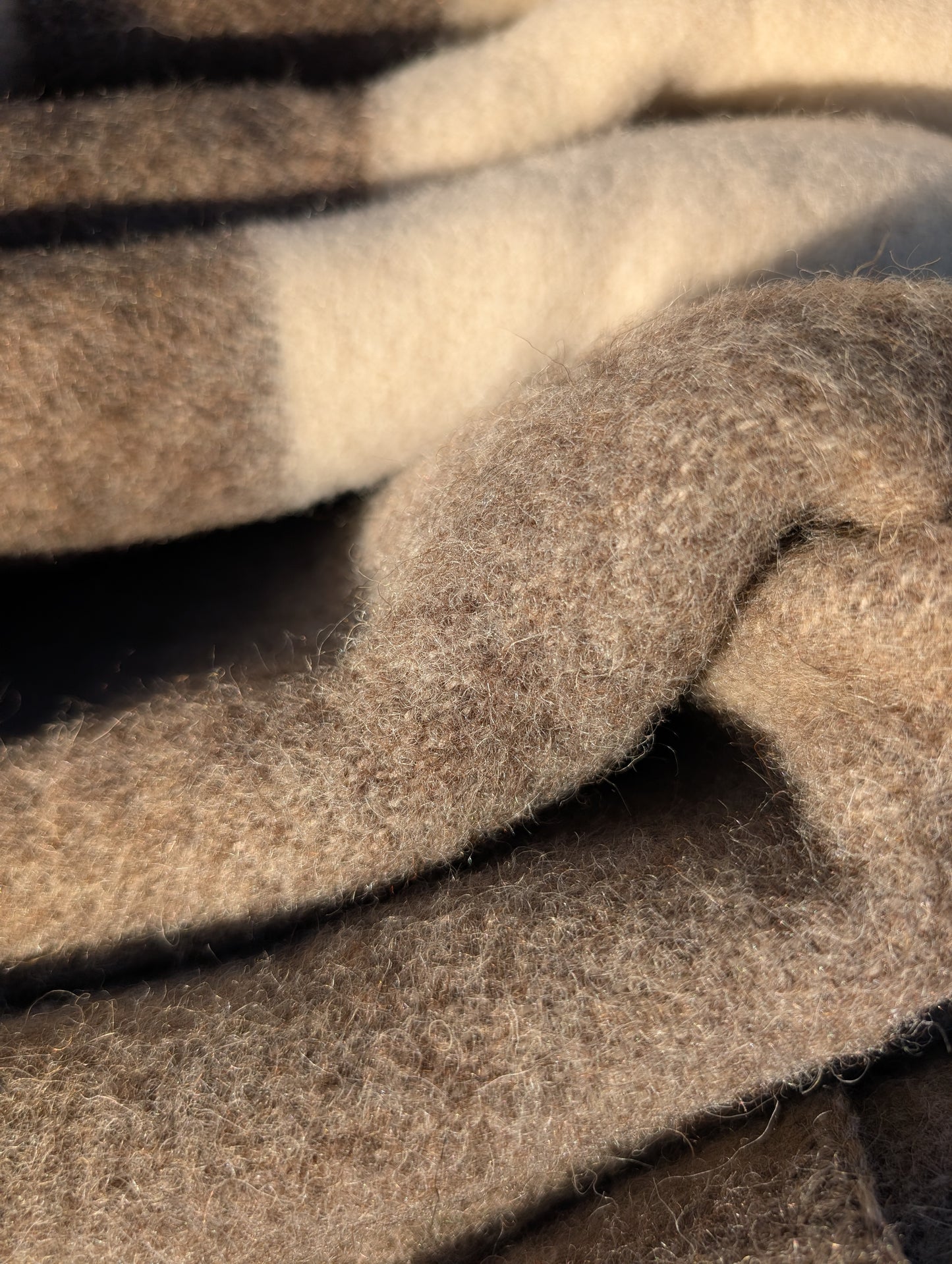 Closeup of a folded premium undyed wool throw in earth natural cream and brown, for rustic and modern home decor and bedding