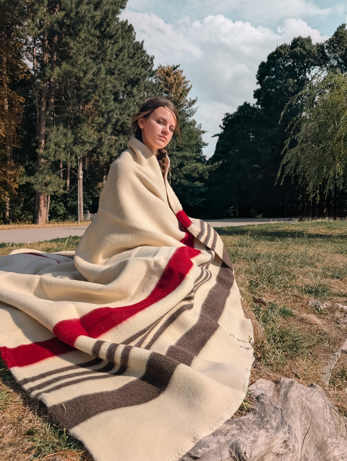 A girl wrapped in a white or beige virgin wool blanket, with red and brown stripes
