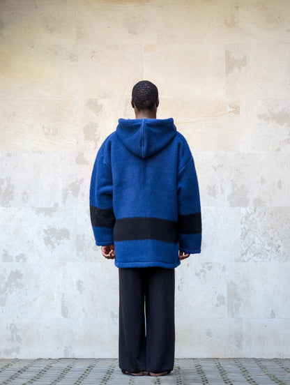 Back view of an oversized royal blue  virgin wool blanket pullover with black stripes.