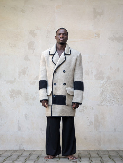Front full-length shot of a model wearing a gray double-breasted wool peacoat with black pipe edging and black stripe accent.