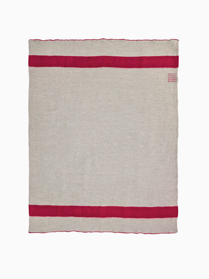 Flat-lay studio view of a heavy grey natural wool blanket with twin horizontal red stripes.
