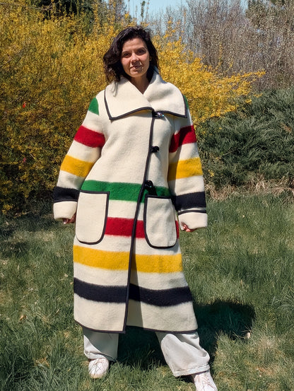 Woman wearing a long wide lapel coat with toggle button closure and 2 big front pockets. Recycled pure wool blanket outerwear.