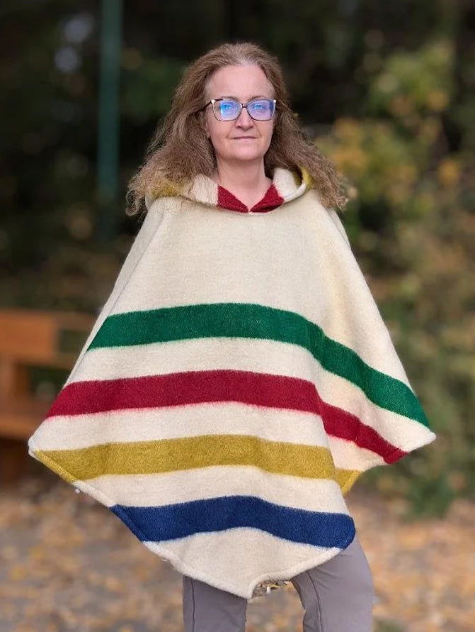 Woman wearing multi stripe poncho made of recycled wool blanket, traditionally handspun, made of 100 percent eco wool. Poncho with hood.