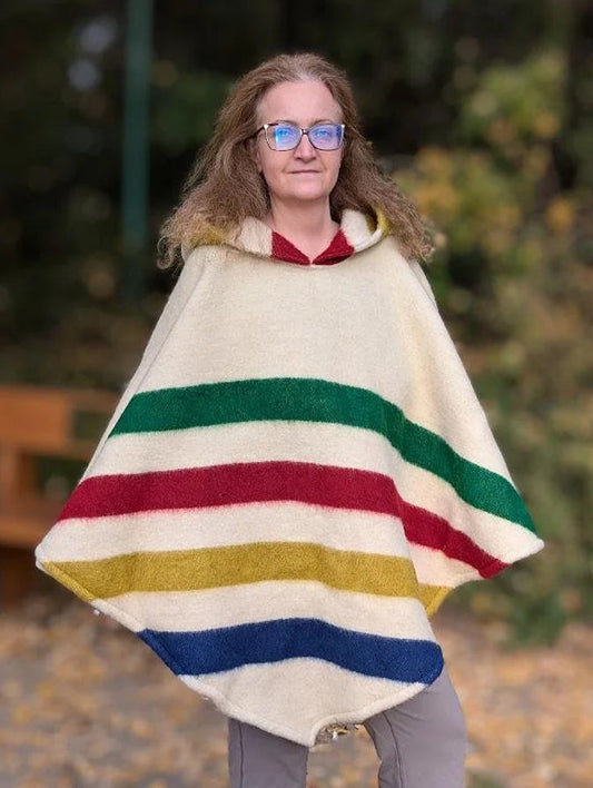 Woman wearing multi stripe poncho made of recycled wool blanket, traditionally handspun, made of 100 percent eco wool. Poncho with hood.