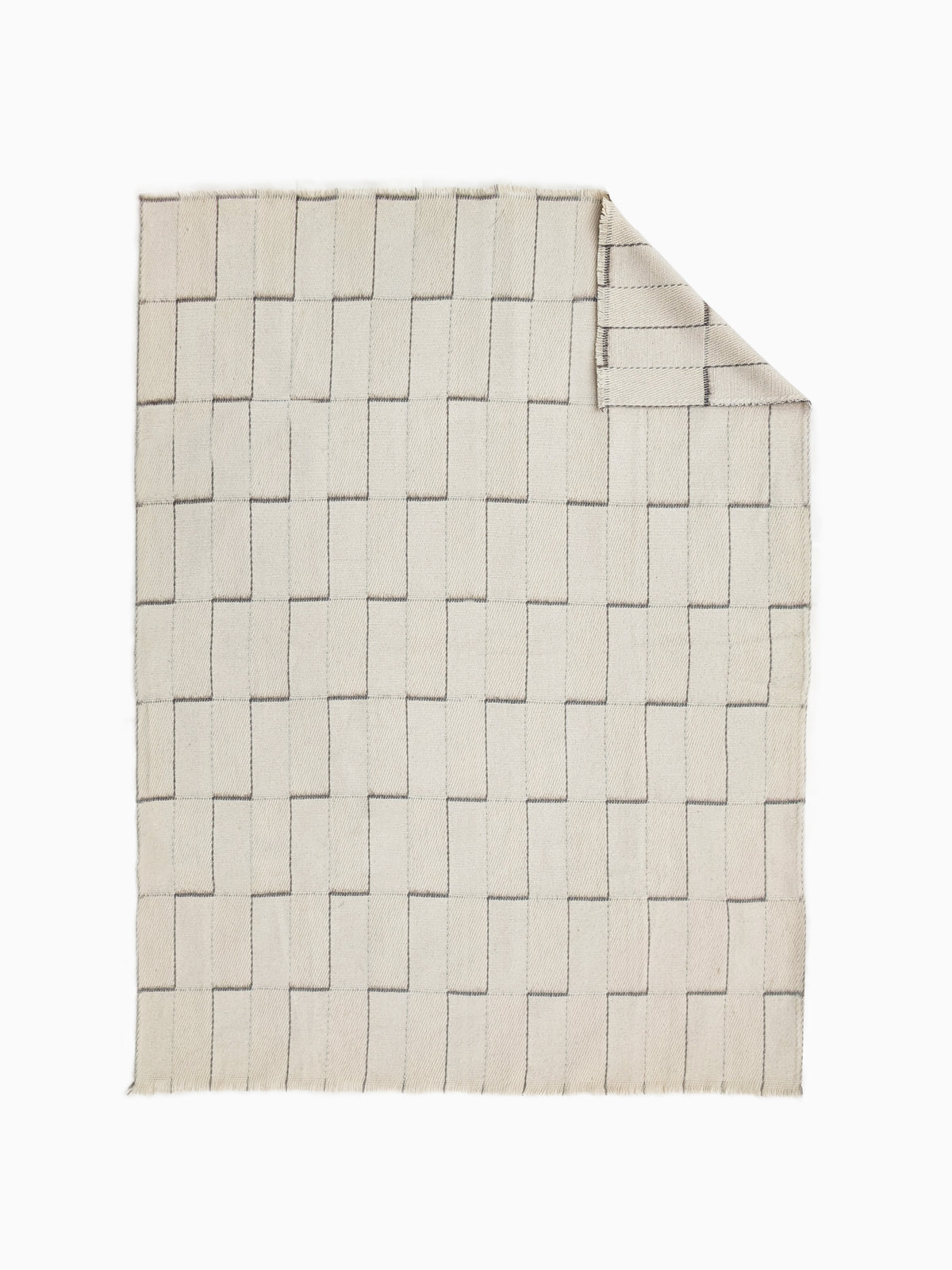 An undyed wool blanket throw in a warm cream or off-white color, with a stepped geometric grid pattern.