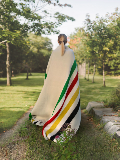Person wrapped in a premium handwoven stripe wool blanket with nature in the background