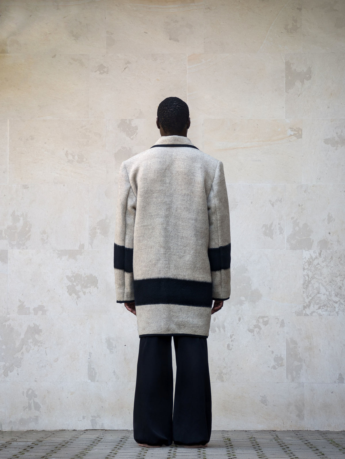 Back view of a light gray handwoven wool blanket coat with peacoat design.