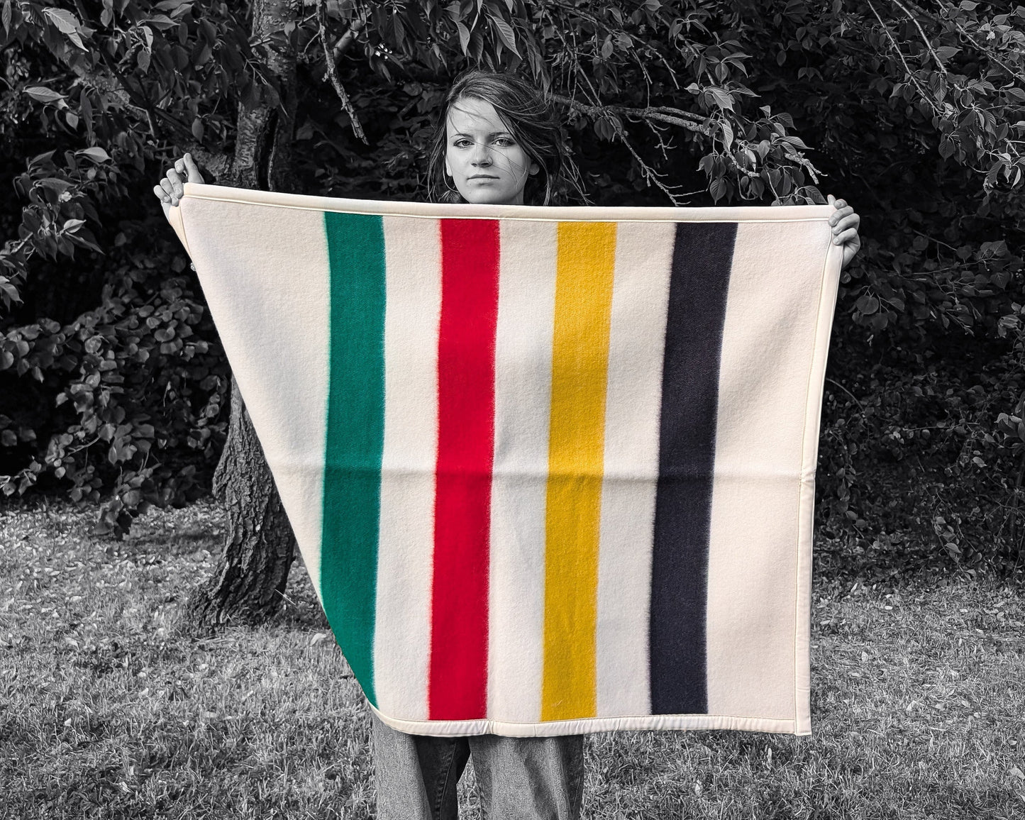 A girl is holding a cozy colorful Baby Blanket: Organic Lambswool Crib Blanket, outdoors