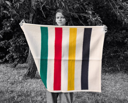 A girl is holding a cozy colorful Baby Blanket: Organic Lambswool Crib Blanket, outdoors