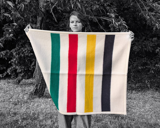 A girl is holding a cozy colorful Baby Blanket: Organic Lambswool Crib Blanket, outdoors
