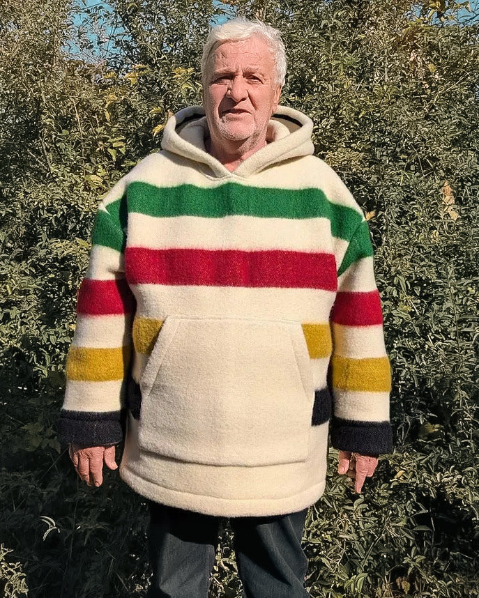 An elderly man wearing a pure wool multi striped blanket hoodie with a big front kangaroo pocket, unisex boreal shirt, camp sweater upcycled from sustainable eco wool blanket