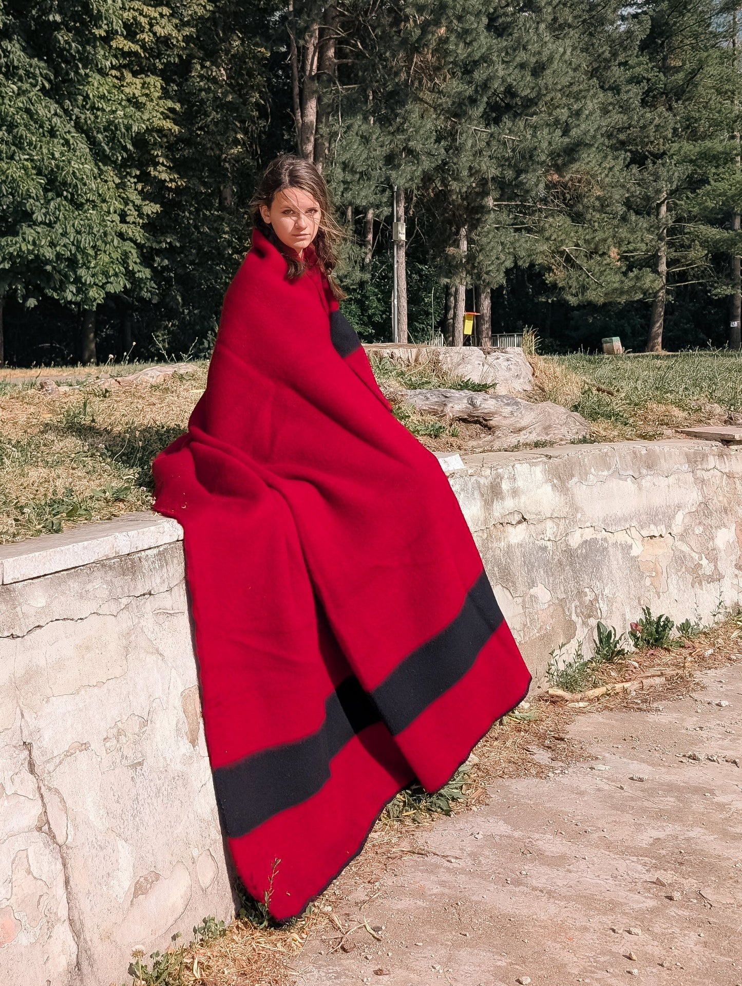 Person covered with a Heritage red wool blanket, with a black stripe.