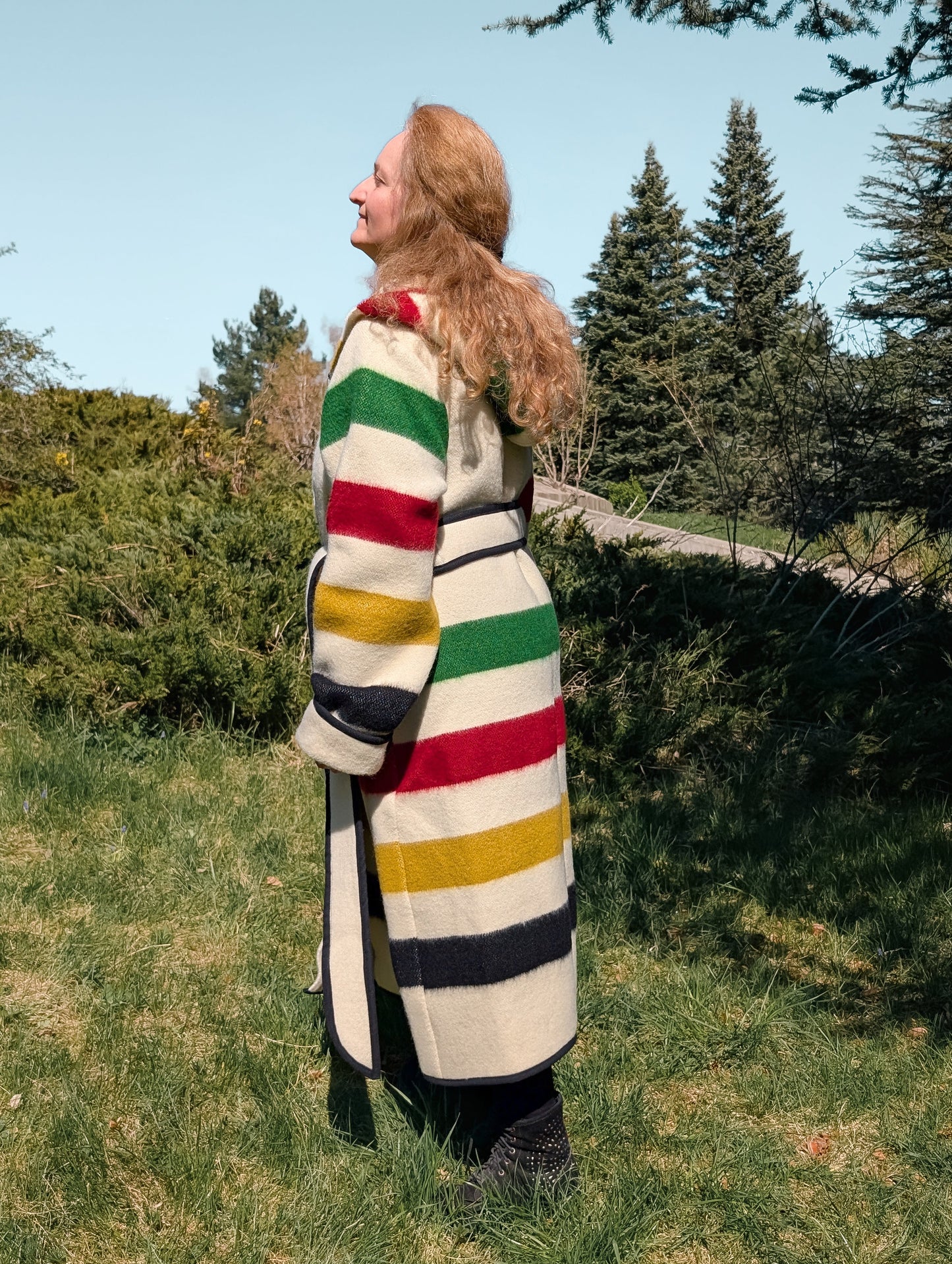 A woman wearing a multistriped blanket capote coat tailored from a new handwoven wool blanket.