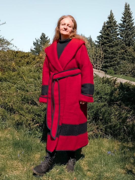 A woman wearing a pure wool capote coat in solid red with a black stripe, upcycled from a single wool blanket.