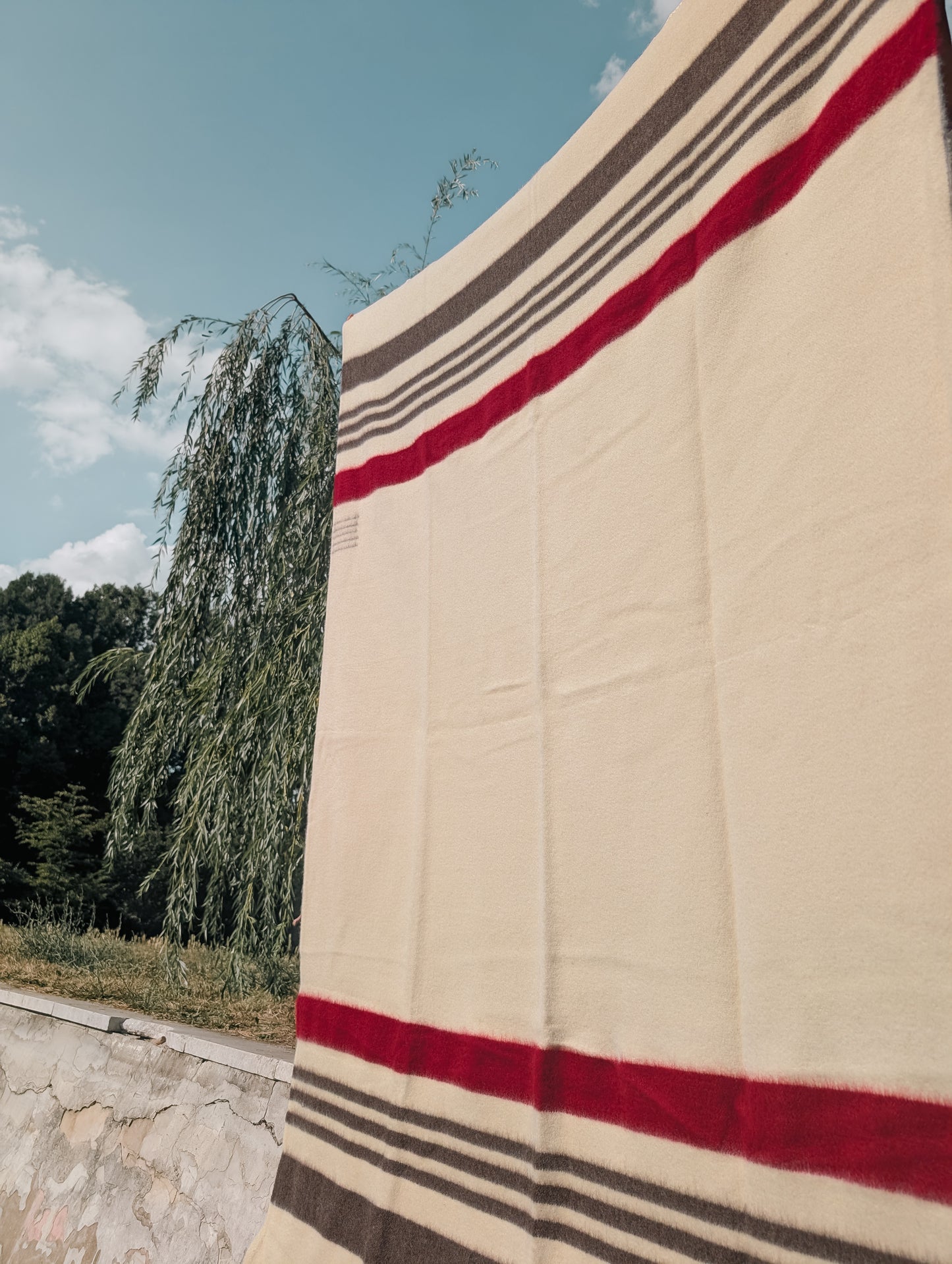 Premium quality heirloom wool blanket with multicolor stripes, hanging in an outdoor setting