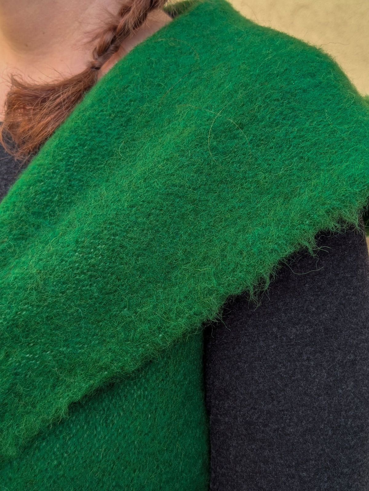Close-up texture detail of handwoven emerald green virgin wool sleeveless waistcoat.
