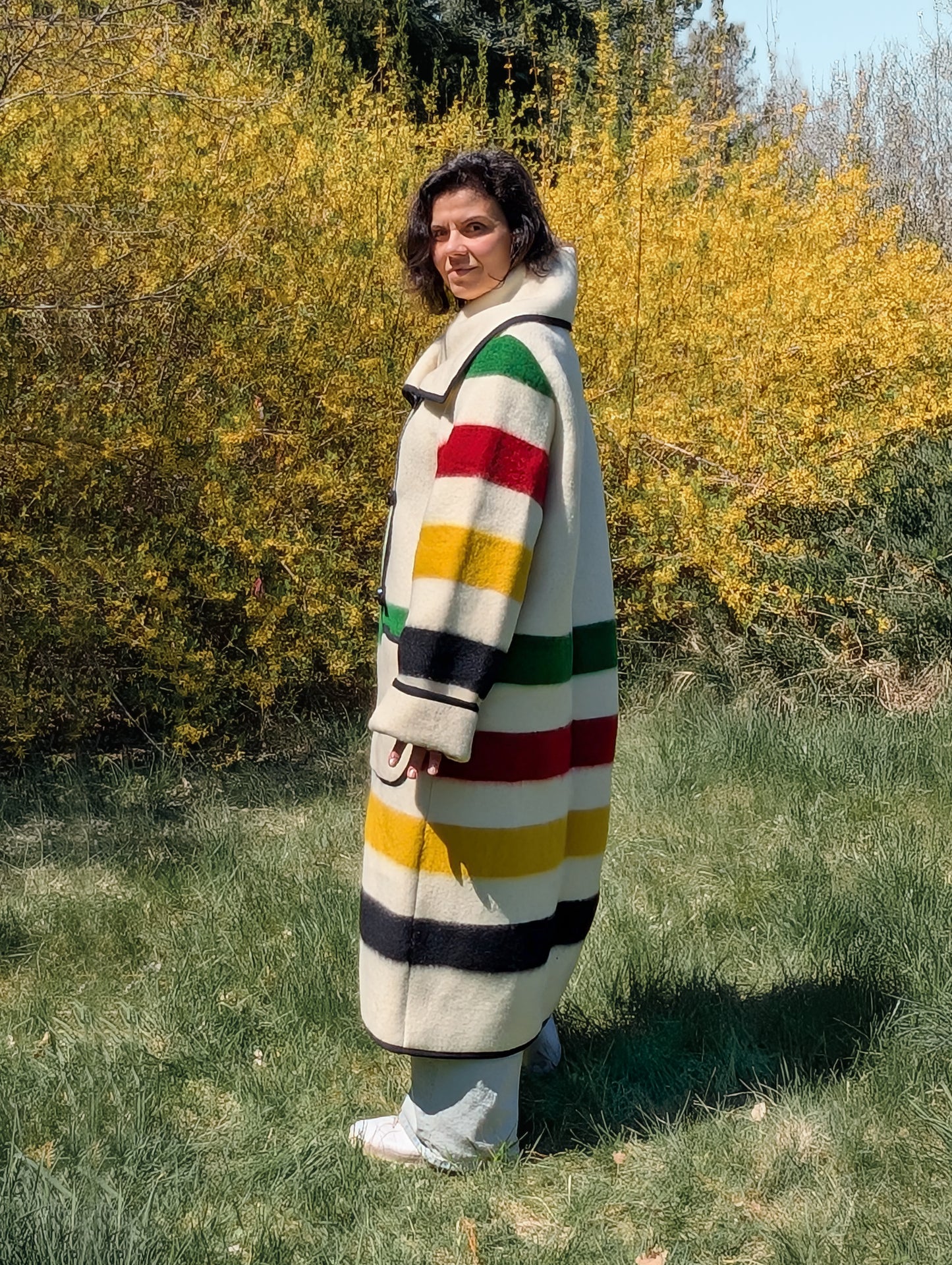 Woman showing the side view of a tailor made long wool collar coat or duster coat, made of recycled ethnic wool blanket.
