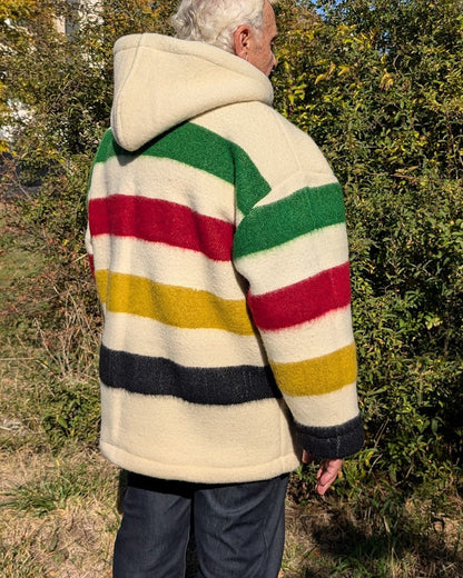 An elderly man wearing a pure wool multistriped anorak with a big front kangaroo pocket, unisex boreal shirt, camp sweater upcycled from sustainable eco wool blanket 