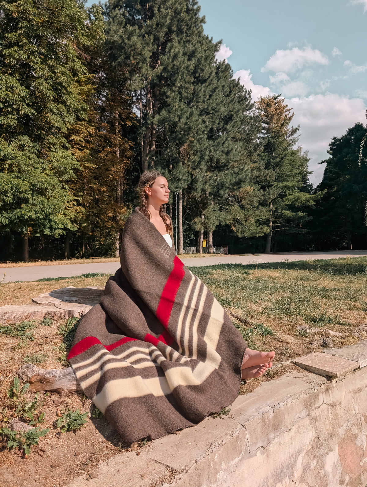 Woman sitting outdoors wrapped in heritage natural brown wool blanket 