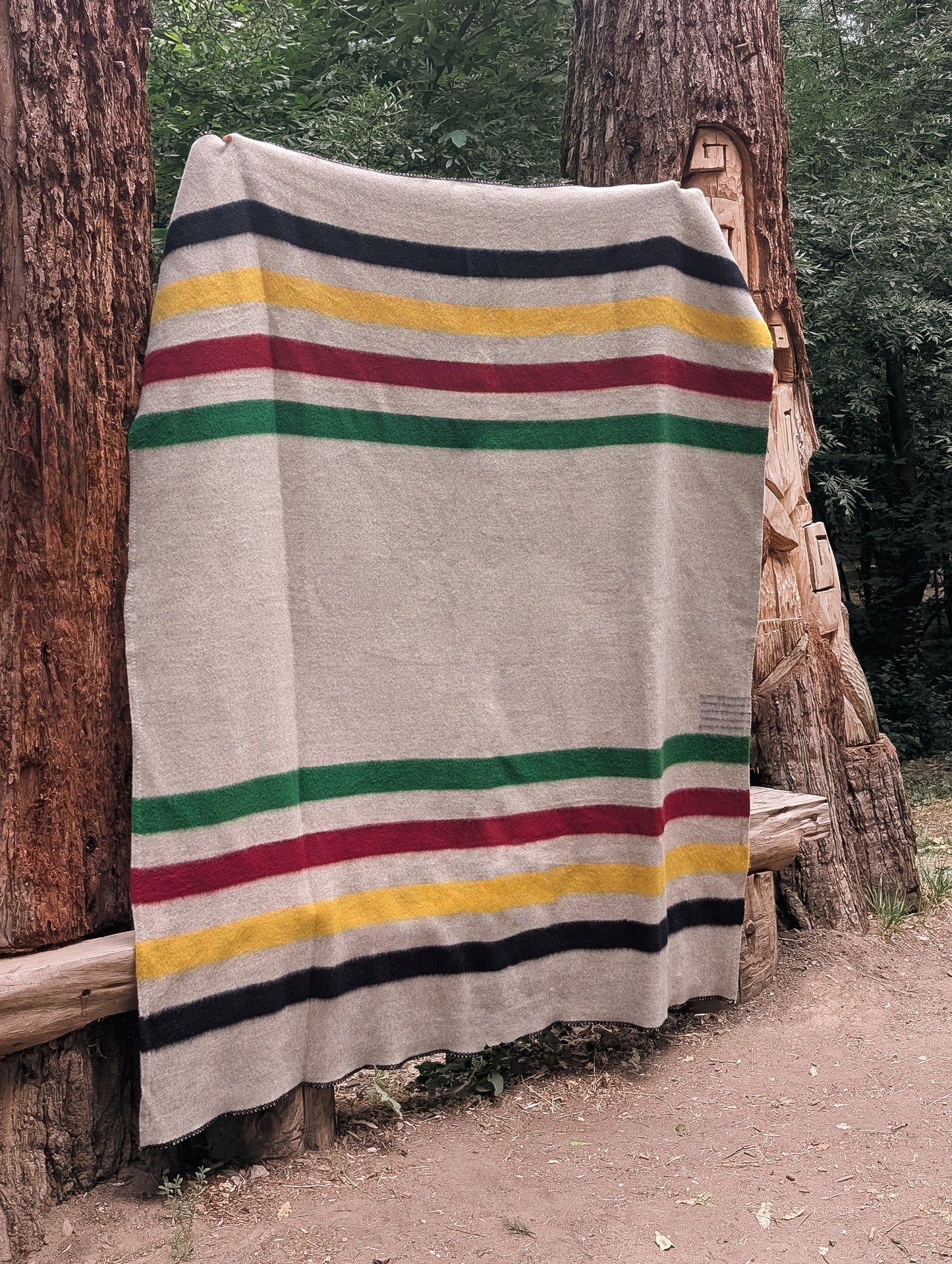heirloom Striped blanket handwoven from pure wool and draped over trees in a forest setting