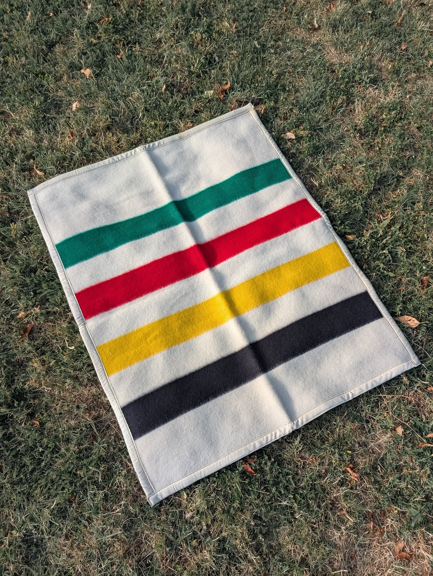 A soft handmade Baby Blanket: repurposed Lambswool Crib Blanket, laid on the grassy ground