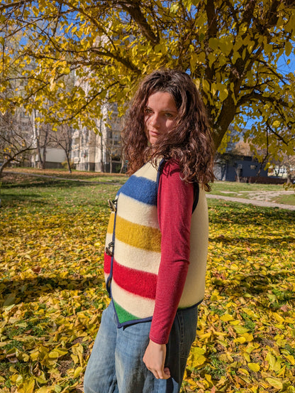 A woman wearing an all-purpose blanket stripe gilet, sleeveless vest suitable on jeans, boho skirts, T-shirts, and knitted sweaters. A bespoke unisex statement garment.