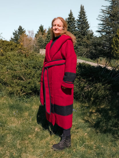 A woman posing with a handmade wool wrap coat with a hood upcycled from a single artisan handwoven red stripe blanket