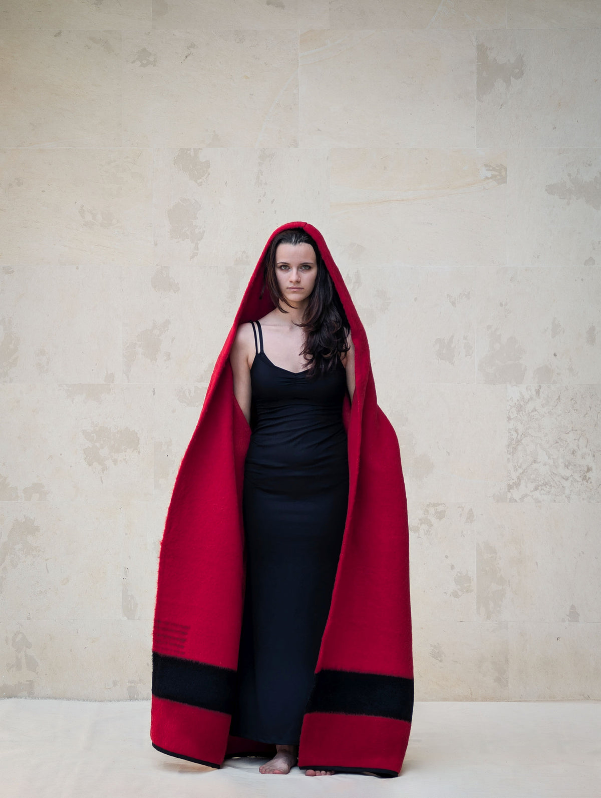 A woman wrapped in a large hooded red wool coat. A stylish quiet slow fashion modern minimalistic outfit.