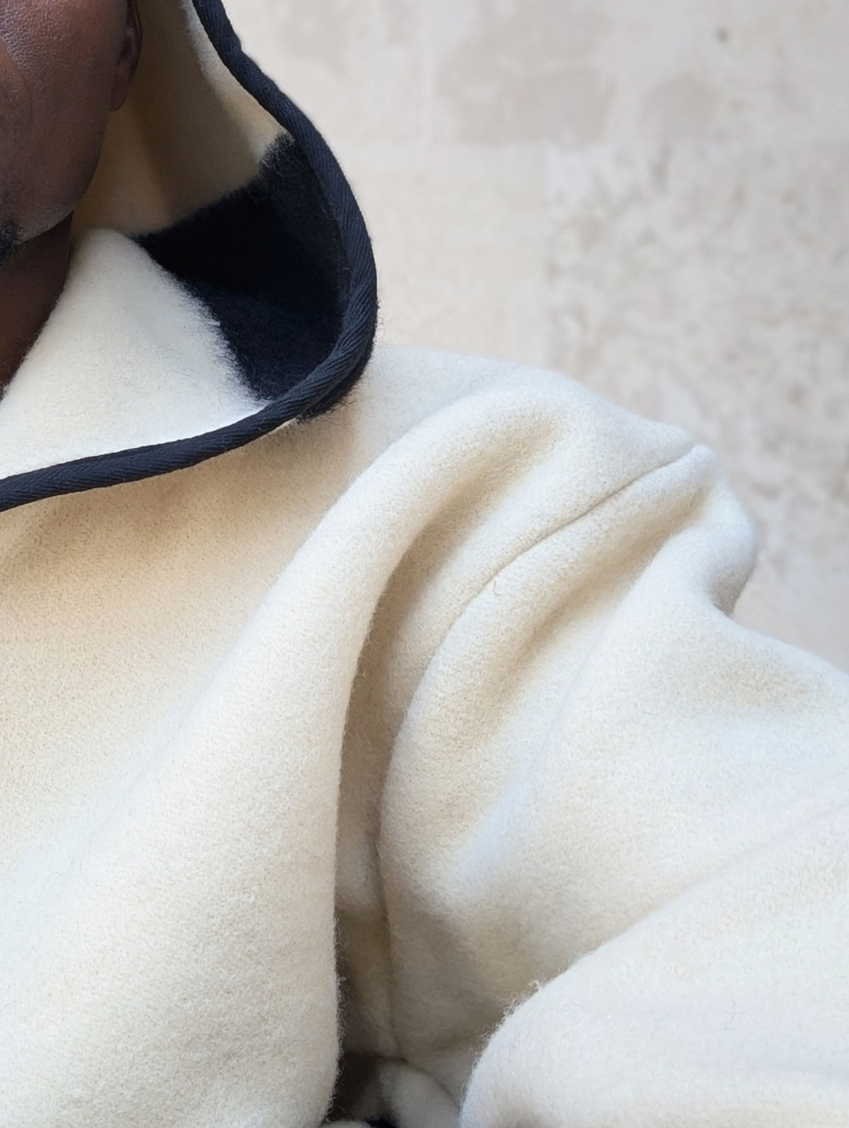 Close-up of a cream-colored wool hoodie tailored from a handmade natural organic blanket. 