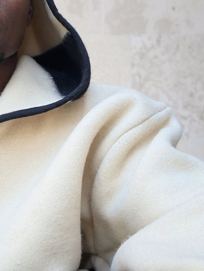 Close-up of a cream-colored wool hoodie tailored from a handmade natural organic blanket. 