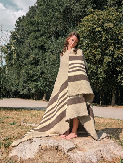 Girl wrapped in a gray wool blanket or cabin throw with gray base, white stripes. Authentic undyed pure wool throw.