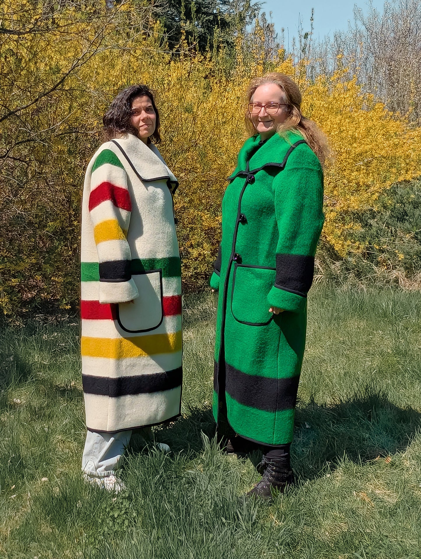 Two models of long wide collar coats in different color and color stripes, repurposed from sustainable natural wool blankets.