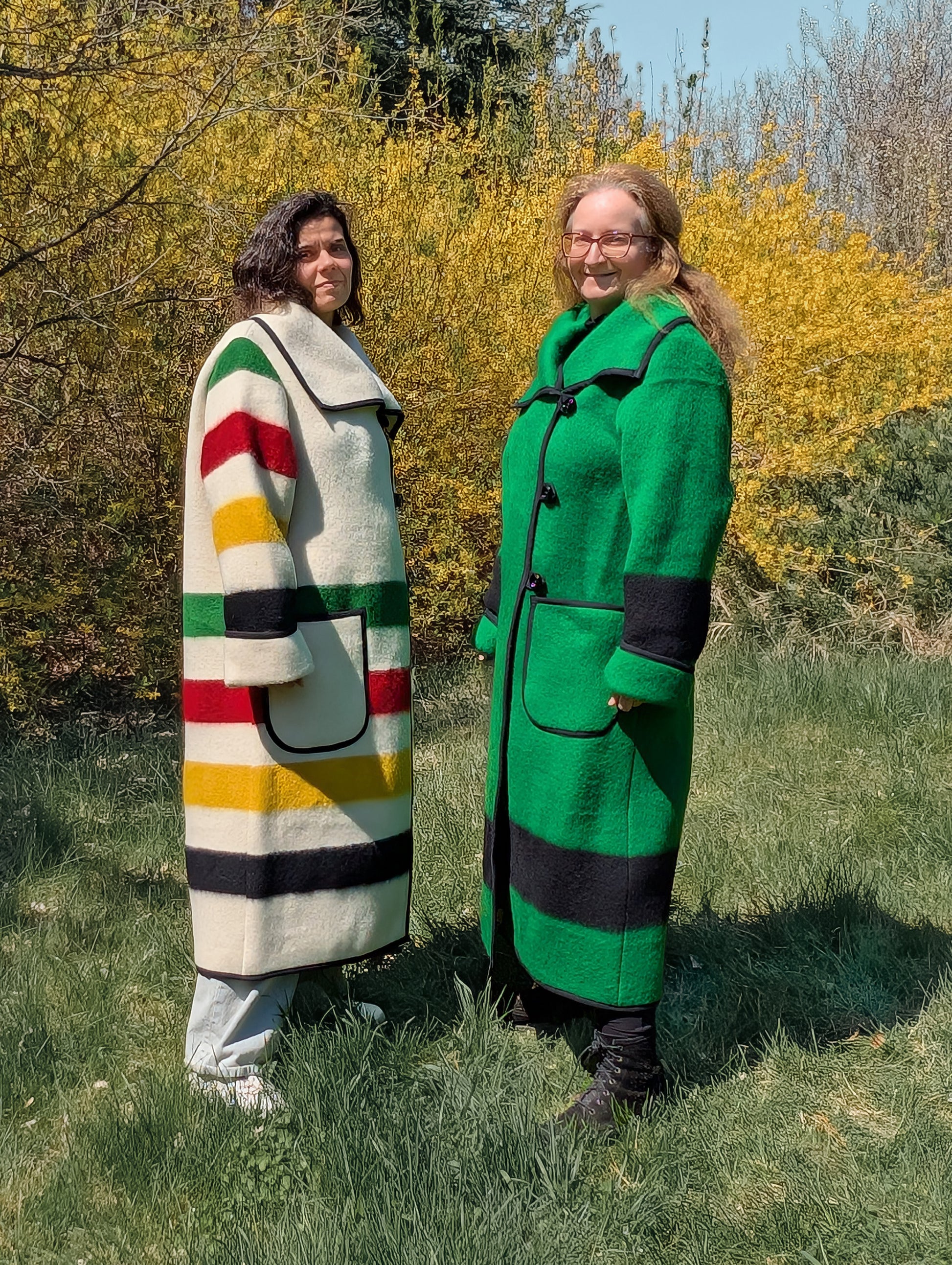 Two models of long wide collar coats in different color and color stripes, repurposed from sustainable natural wool blankets.