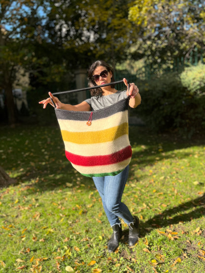 Woman holding a handmade shoulder bag in traditional authentic multicolor stripes, recycled from iconic handwoven wool blanket