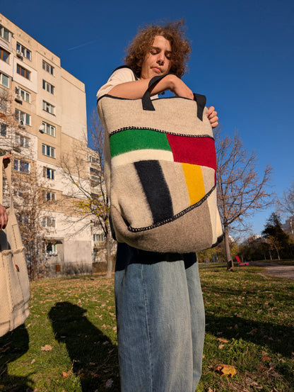 Young man hoding a modern unisex shoulder bag with stylish designer patchwork of all natural wool blanket leftovers.