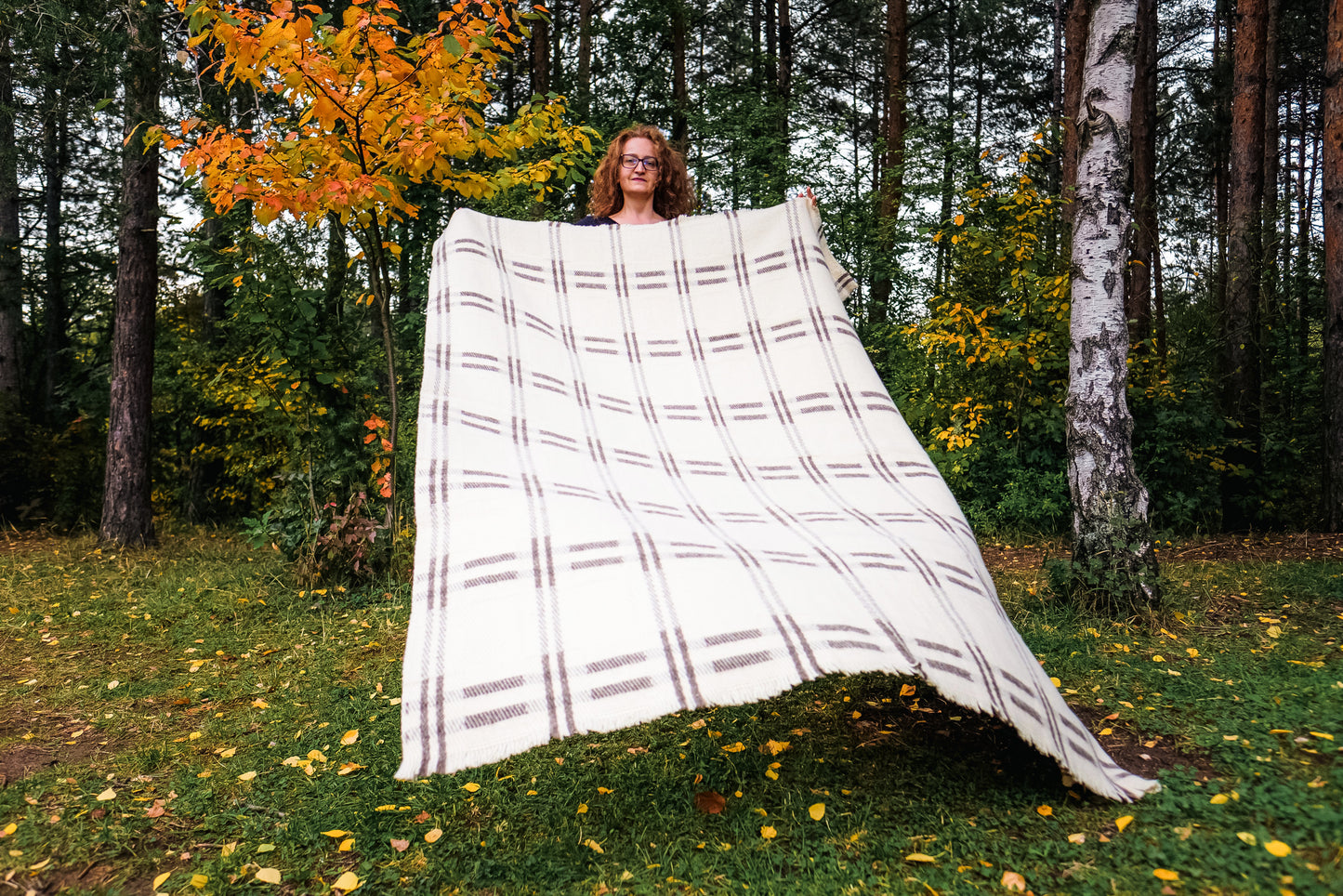 Woman holding an undyed pure wool blanket throw best for minimalistic home decor, rustic or hygge style 