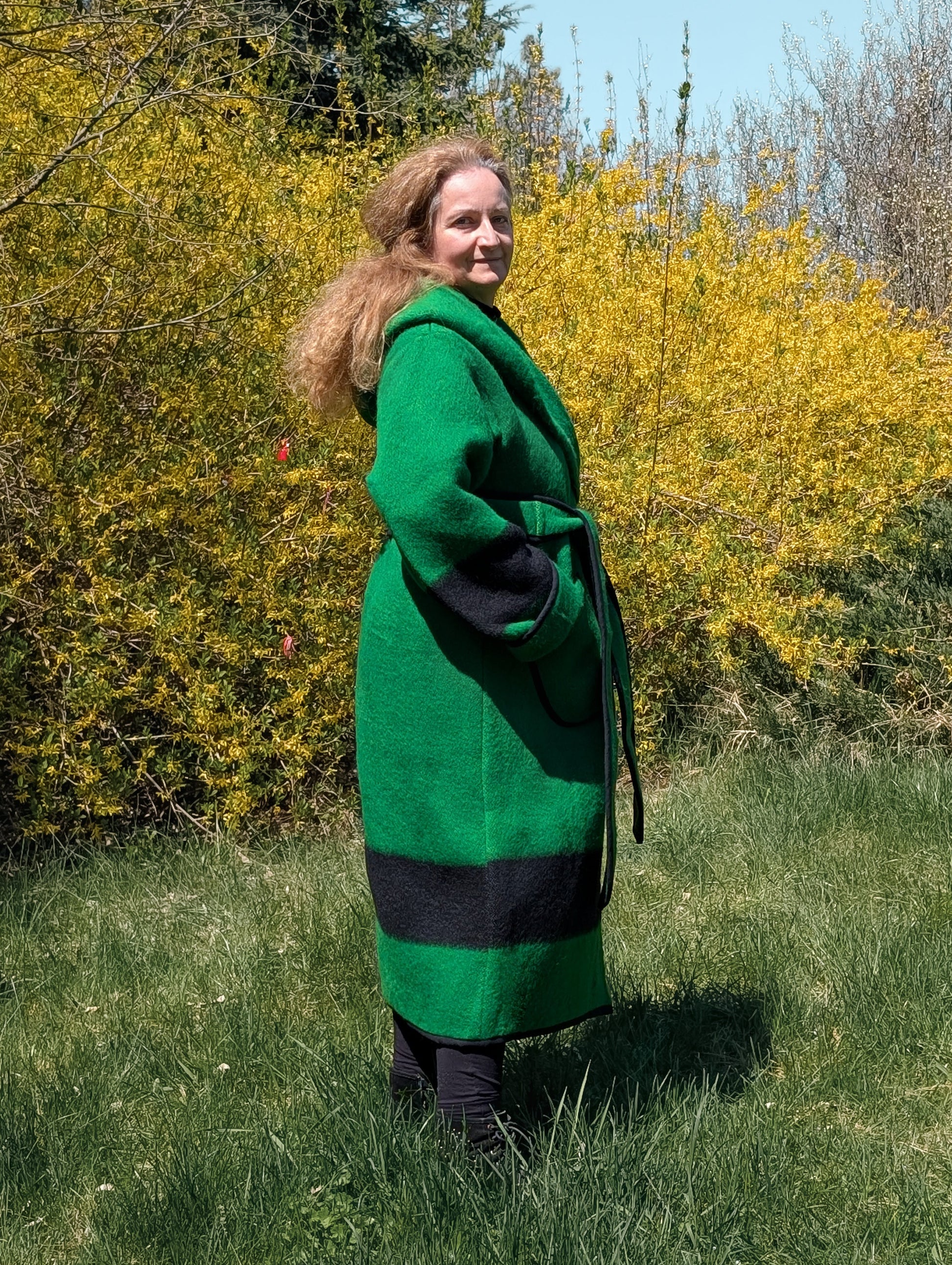 Side view of long wrap coat with a wide hood and belt made from upcycled virgin wool blanket. 