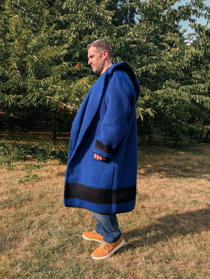 Man wearing a long blue wrap frontier capote coat in native american style. The coat can be worn loose or belted.
