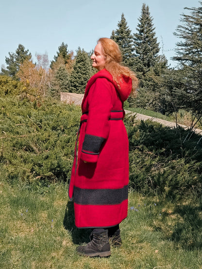 A lady wearing a pure wool custom made capote coat made from a single red stripe blanket, cinched with a belt from the same fabric.