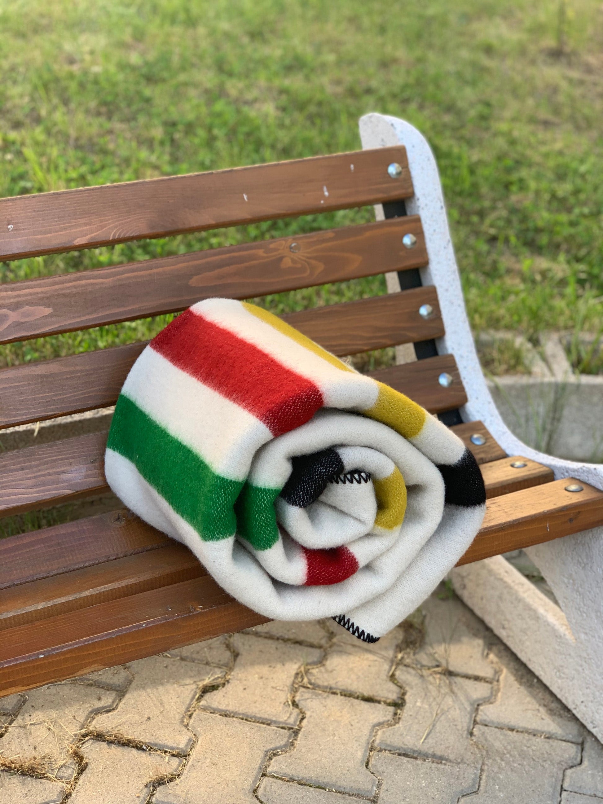 Off-white Multistripe wool inspired vintage wool throw with colorful stripes rolled on a bench.