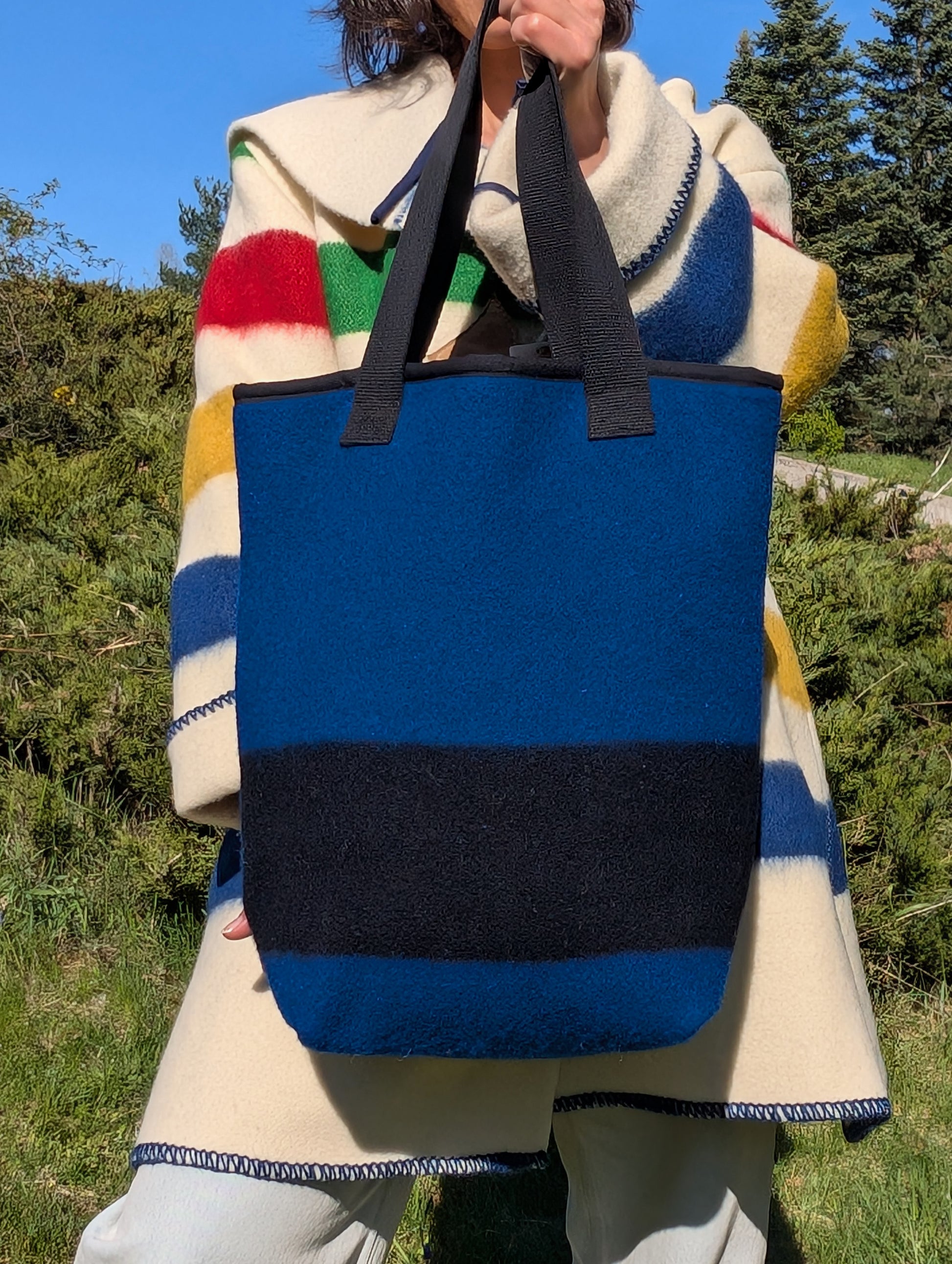 Person holding a blue tote bag with black stripe made from iconic heritage blanket