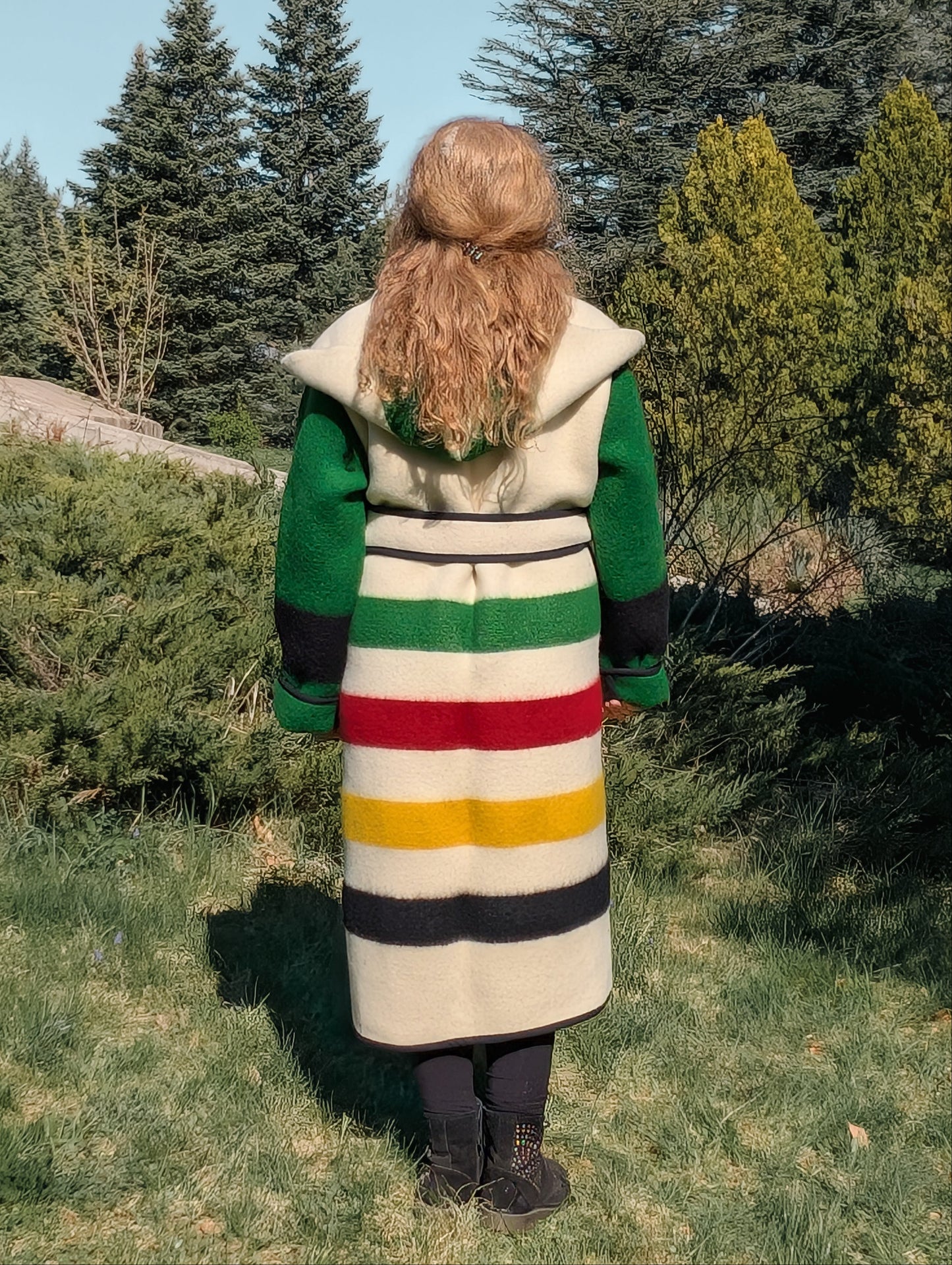 A woman wearing a statement blanket capote coat with iconic stripes and a hood. 