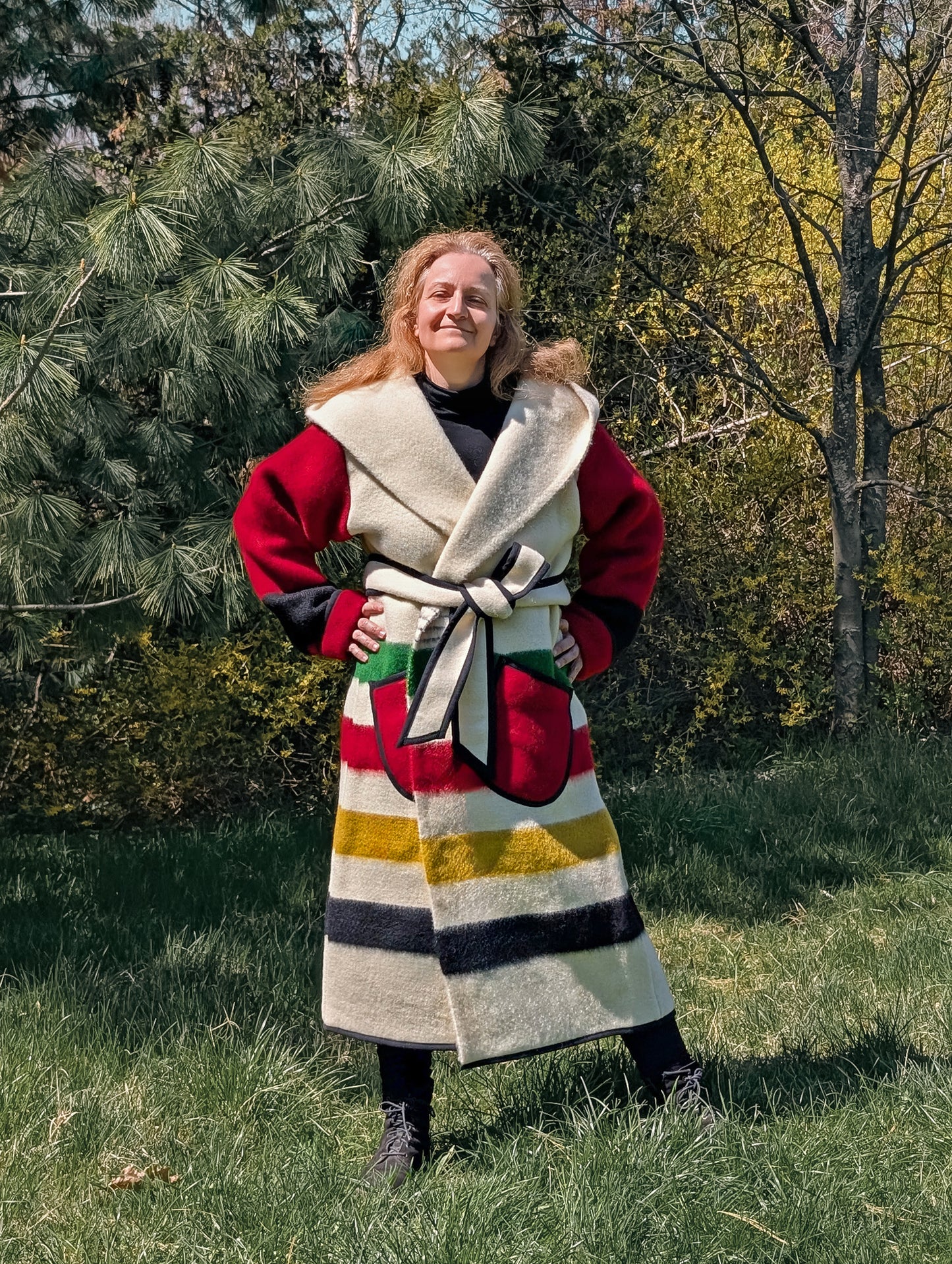 Woman posing with a unisex stripe duster with multi stripes and red sleeves, cinched with a belt. This model is handmade from authentic bulgarian blanket.