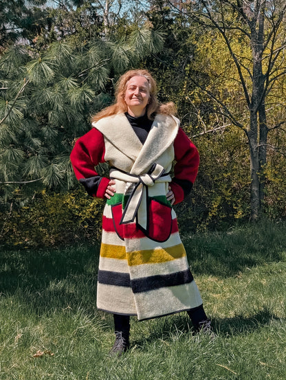 Woman posing with a unisex stripe duster with multi stripes and red sleeves, cinched with a belt. This model is handmade from authentic bulgarian blanket.